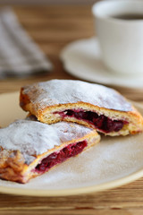 slices of strudel from puff pastry with a cup of tea on a wooden table