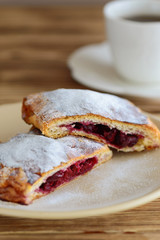 slices of strudel from puff pastry with a cup of tea on a wooden table