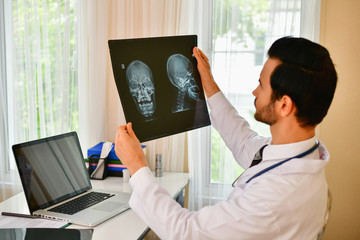 Smiling doctor posing in the office, he is wearing a stethoscope, medical staff on the hospital background