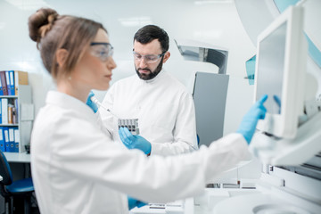 Laboratory assistants in unifrom working with professional medical analizer at the laboratory