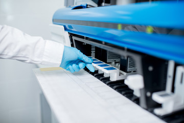 Close-up view on the hand putting samples into the medical analyzer