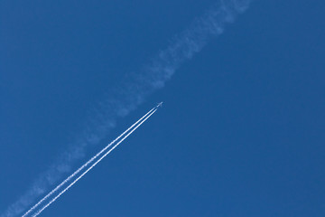 Flugzeug mit Kondensstreifen am blauen Himmel