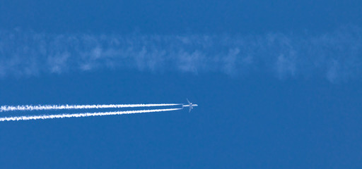 Flugzeug mit Kondensstreifen am blauen Himmel