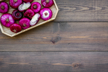 Obraz na płótnie Canvas Red onion is healthy product. Onion bulbs in tray on dark wooden background top view copy space