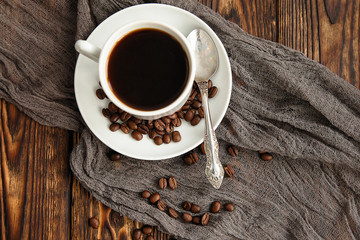 coffee Express triple in white Cup next to coffee beans scattered on dark vintage wooden table