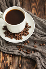 coffee Express triple in white Cup next to coffee beans scattered on dark vintage wooden table