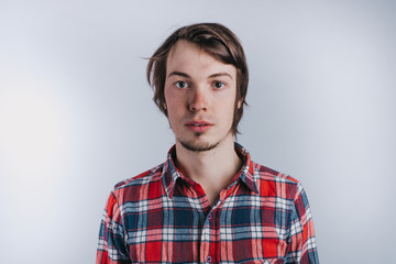 Portrait of a man in a plaid shirt on a white background, a man without emotions, copy space - isolated