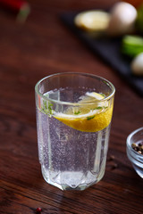 Glass of water with fresh lemon on wooden background, close-up, selective focus