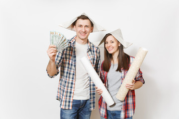 Young happy woman, man in casual clothes holding bundle of dollars, cash money and wallpaper roll. Couple isolated on white background. Instruments for renovation apartment room. Repair home concept.