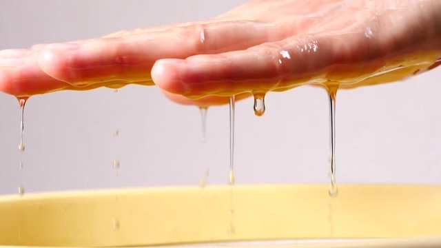 Close up slow motion shot of unrecognizable woman putting hand into paraffin bath taking care of hands skin.