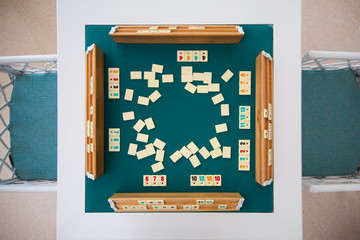 Turkish board game Okey (Rummikub). A table with green cloth and chips. Hands of the players.