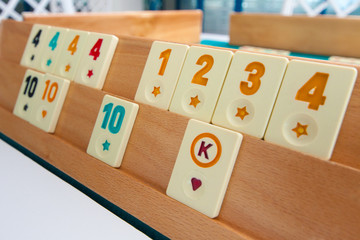 Turkish board game Okey (Rummikub). A table with green cloth and chips. Hands of the players.