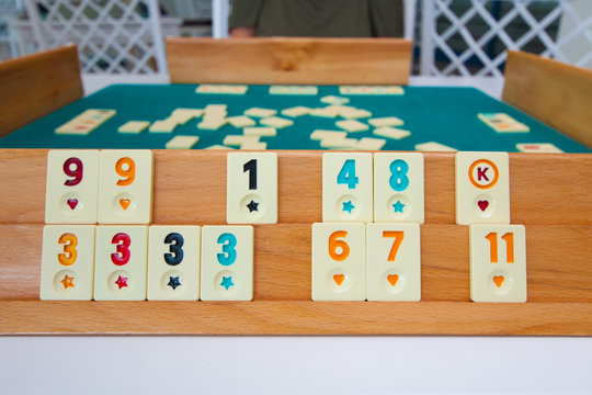 Turkish board game Okey (Rummikub). A table with green cloth and chips. Hands of the players.