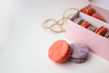 orange purple macaroons cakes next to the pink packaging with ropes