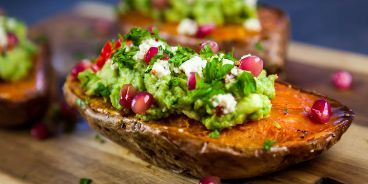 Healthy dinner - Baked sweet potatoes served with guacamole, feta cheese and pomegranate