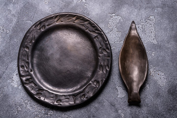 Empty black ceramic plate on grey background
