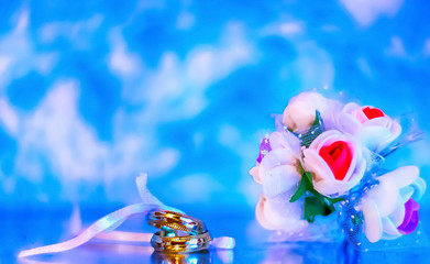 Wedding rings on a glamorous background with flowers