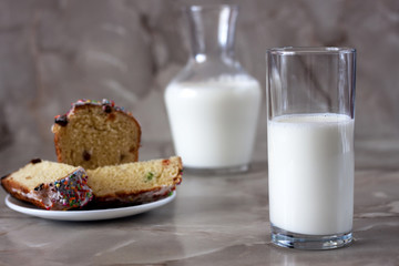 Delicious aromatic cake and a glass of milk on a table with a marbled background.