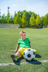 Positive boy child playing football on the field.