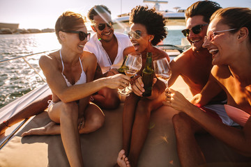 Multiracial friends toasting drinks on the yacht deck - Powered by Adobe