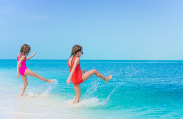 Fototapeta na wymiar Little happy girls splashing. Kids running to the turquoise water ready to swim