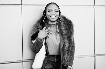 Rich african american girl in red coat and fur against golden wall. Black stylish woman.