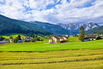 Fototapeta na wymiar Austrian village among meadows fields and Alpine mountains.
