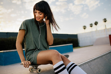 Beautiful girl listening music with earphones at skate park © Jacob Lund