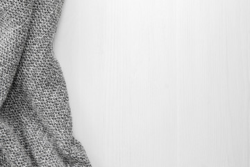 Gray knitted cloth on a white wooden background.