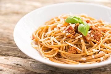 Piatto di spaghetti condito con carne, pomodoro e parmigiano 