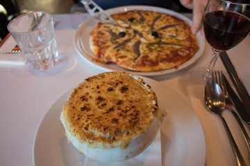 onion soup and pizza on white plates 