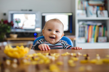 Cute little toddler boy eating cornflakes and smiling