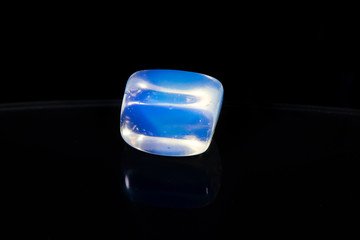 One single isolated crystal on the black shiny surface and black background