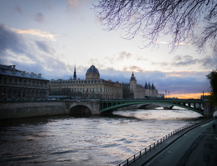 beautiful Parisian bridge against the backdrop of a magically setting sun seen in the early windy spring evening