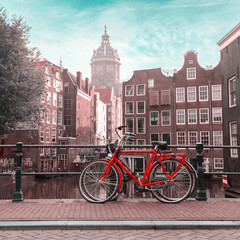 Fototapeta na wymiar Houses and Boats on Amsterdam Canal. Morning photo of colored houses in the Dutch style and bridge with a red bicycle in the foreground