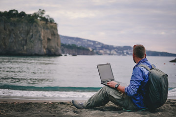 man, guy the photographer working with a laptop on the beach, backpack, concept of find information...