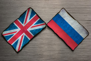 Fototapeta na wymiar Flags of the United Kingdom and Russia side by side on dark grey brushed metal background