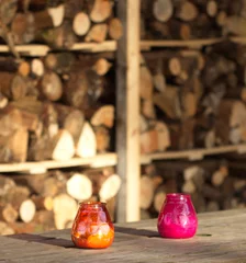 Foto op Plexiglas twee kaarsen op een achtergrond van gestapeld hout © JoveImages