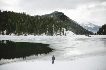 Boy standing at edge of frozen lake 