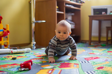 Beautiful little baby boy, toddler smiling at camera, animals and dinosaurs around him, indoor shot in kids playroom