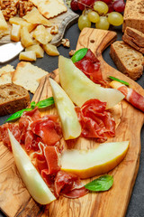 melon with prosciutto on olive woonen cutting board