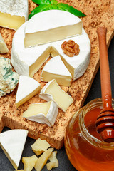 Fresh Brie or camembert cheese on wooden board with nuts and honey