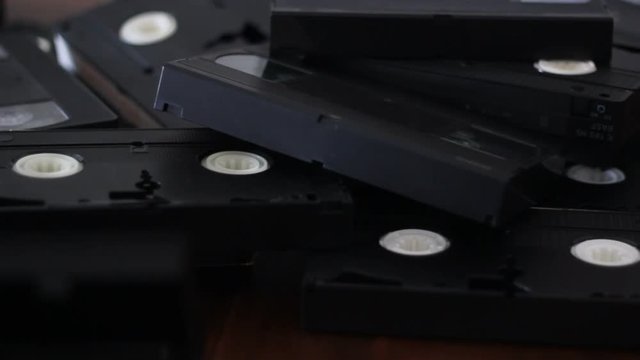 Take a vhs cassette tape from a stack of tapes
