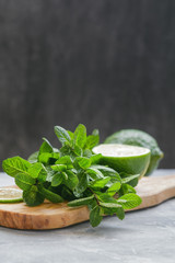 Fresh mint and lime on a wooden cutting board on a table. Food background. Copy space.