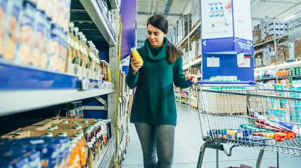 woman in store read ingredients of juice. grocery shopping. copy