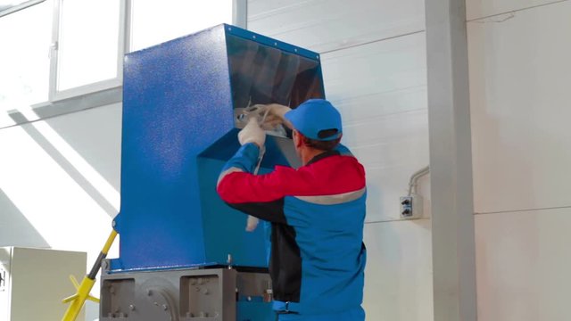 Worker loads sorted plastic in automated plastic recycling machine