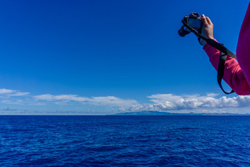 Tourist traveler photographer taking pictures seascape on photo camera on background ocean