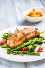 Wallpaper murals Fish Roasted salmon steak with asparagos broccoli carrot tomatoes radish green beans and peas. Fish meal with fresh vegetable