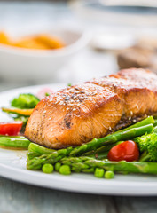 Roasted salmon steak with asparagos broccoli carrot tomatoes radish green beans and peas. Fish meal with fresh vegetable
