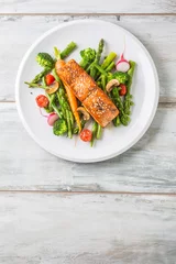 Foto auf Glas Roasted salmon steak with asparagos broccoli carrot tomatoes radish green beans and peas. Fish meal with fresh vegetable © weyo